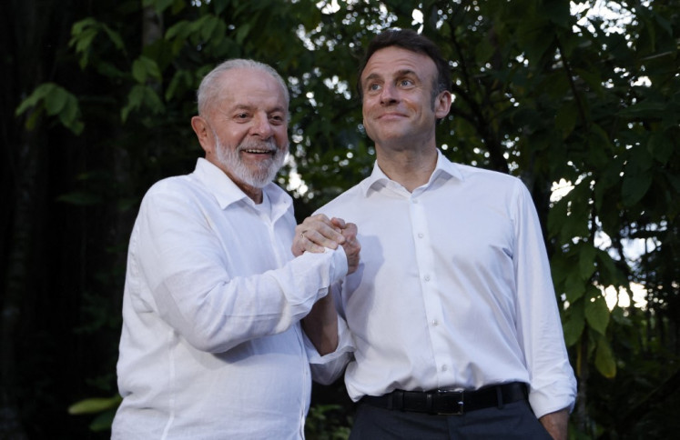 Brazilian President Luiz Inacio Lula Da Silva (left) and French President Emmanuel Macron react on arrival at Combu Island, in front of Belem, state of Para, Brazil, on March 26, 2024. 