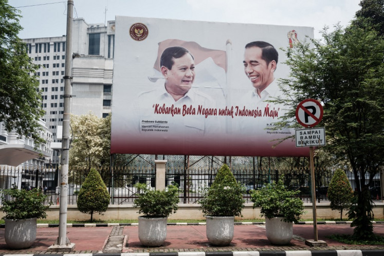 A billboard displays portraits of President Joko “Jokowi“ Widodo (right) and Defense Minister Prabowo Subianto in front of the Defense Ministry office in Jakarta on March 28, 2024.