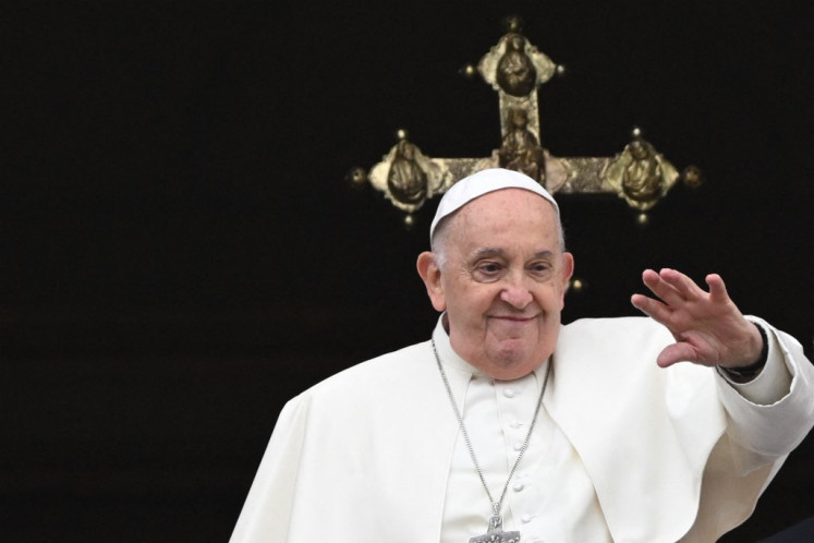 Pope Francis waves from the central loggia of St. Peter's basilica during the Easter 'Urbi et Orbi' (to the city and the world) message and blessing as part of the holy week celebrations, in the Vatican, on March 31, 2024.