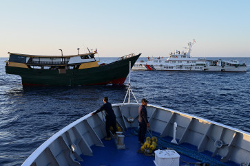 A China Coast Guard vessel (back right) sails on March 5, 2024, near the Philippine military-chartered Unaizah May 4 (left) during its supply mission to Second Thomas Shoal in the disputed South China Sea. 