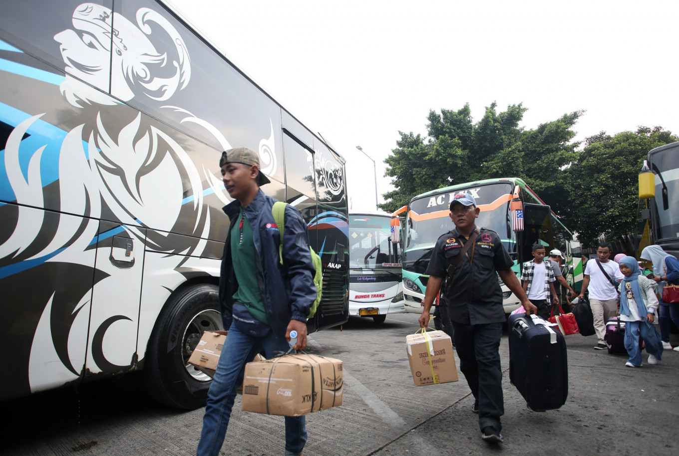 Travelers approach their bus at the Kalideres bus station in Jakarta on April 4, 2024.