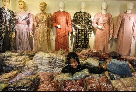 Ramadan shopping: A visitor examines Muslim outfits on April 2, 2024, at a shop in Medan central market in North Sumatra. Garment sales increased three weeks into the Ramadan fasting month, traders said.