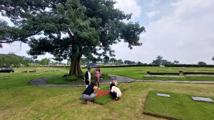 Family pilgrimage: 33-year-old Johanes Randy Prakoso (with umbrella), visits his late father’s grave at San Diego Hills Memorial Park in Karawang, West Java on April 3, 2024. Randy recounts how fortunate his family was that all the costs of his father's funeral was borne by the company that once employed him.