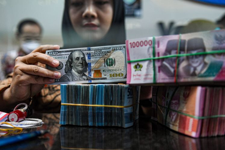 Cash only: A teller arranges stacks of United States dollar and rupiah bills on March 1, 2024, at a money changer in Jakarta.