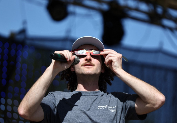 A. David Weigel, INTUITIVE Planetarium director at the US Space & Rocket Center, demonstrates how to wear eclipse glasses for the upcoming April 8 solar eclipse, at the Total Eclipse of the Heart festival, on April 07, 2024 in Russellville, Arkansas. 