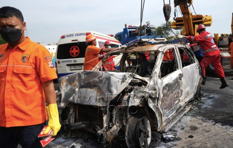 This picture taken in Cikarang, West Java on April 8, 2024 shows rescue workers checking the wreckage of a minivan after it crashed killing 12 people. 