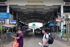 People walk past vehicles crossing over into Thailand from Myanmar at the Tak border checkpoint in Thailand's Mae Sot district on April 10, 2024. Thai armored cars patrolled the town of Mae Sot on April 10 as the deep boom of artillery thundered across from the border in Myanmar where the junta and an ethnic armed group fought for a second day near a vital trade hub.