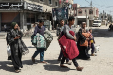 Palestinians carry belongings as people fleeing conflict leave their homes, in the Nuseirat refugee camp in central Gaza on April 12, 2024, amid the ongoing conflict between Israel and the Palestinian militant group Hamas. Authorities in the Hamas-ruled coastal Palestinian territory on April 12 reported dozens of new air strikes in Gaza's central region.
