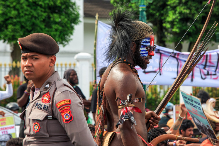 A Papuan man (right) in traditional
clothing and with his face painted in the colors of the Morning
Star Flag, which is banned by Indonesia, stands next to a
policeman during a demonstration in Yogyakarta on December 1, 2023, demanding a referendum on the independence of Papua.