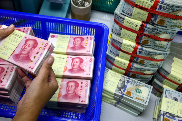 A bank employee counts China's renminbi or yuan notes next to US dollar notes at a Kasikornbank branch in Bangkok on Jan. 26, 2023.