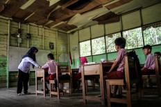 A teacher guides pupils on April 17, 2024, in a classroom with a damaged ceiling at SDN 1 Petuk Katimpun state elementary school in Palangkaraya, Central Kalimantan. The principal has said the school is in such a precarious condition it poses a safety hazard.