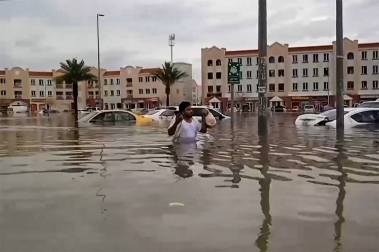 In this video grab from AFPTV, a man wades through a flooded street in Dubai on April 16, 2024. Dubai, the Middle East's financial centre, has been paralysed by the torrential rain that caused floods across the UAE and Bahrain and left 18 dead in Oman on April 14 and 15. 