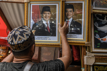 A vendor in Pasar Baru, Central Jakarta, puts up the photos of Prabowo Subianto and Gibran Rakabuming Raka as the president- and vice-president elect on April 23, 2024.