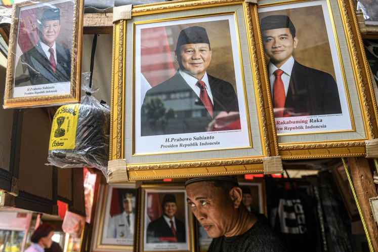 A vendor in Pasar Baru, Central Jakarta, puts up photos of Prabowo Subianto and Gibran Rakabuming Raka as the president- and vice-president-elect on April 23, 2024, one day after the Constitutional Court rejected election dispute petitions filed by losing candidates Anies Baswedan and Ganjar Pranowo.