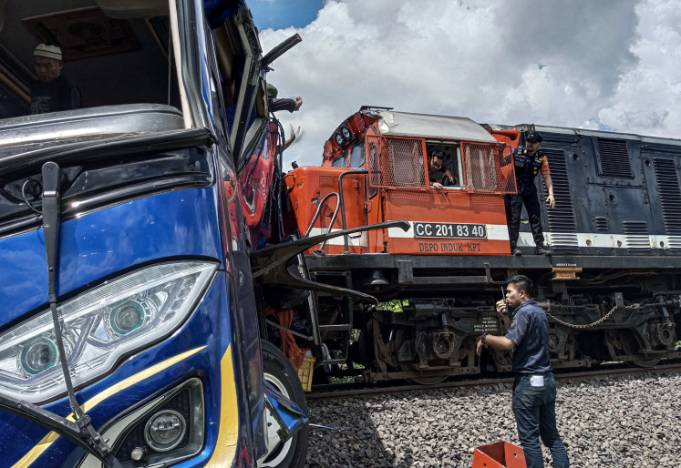 Workers remove a bus that was hit by a train serving the Palembang-Bandar Lampung route at an unguarded railroad crossing in Martapura district, East Ogan Komering Ulu regency, South Sumatra on April 21, 2024. 