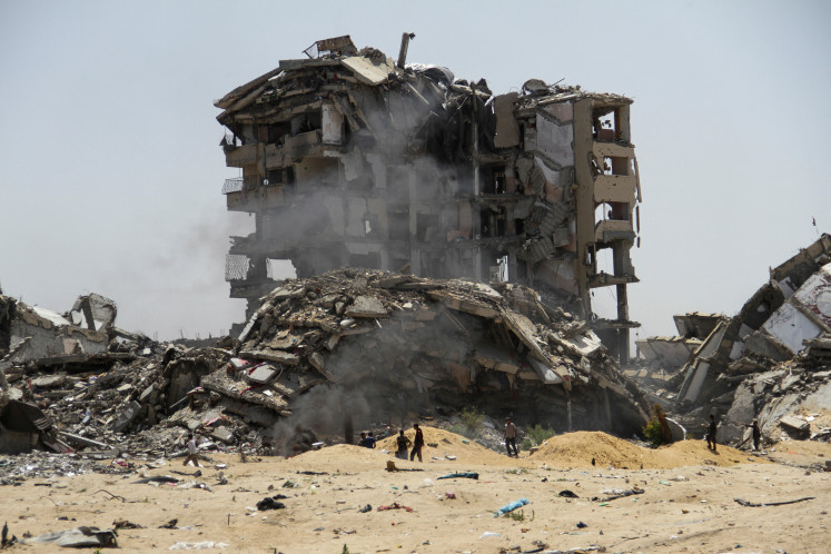 Palestinians walk on April 22, 2024, past the rubble of residential buildings destroyed by Israeli strikes in the northern Gaza Strip. The death toll in the 200-day-old conflict continues to rise. 

