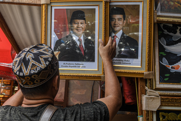 A trader arranges the official portraits of president-elect Prabowo Subianto (left) and vice president-elect Gibran Rakabuming Raka on April 23, 2024, at his kiosk in Pasar Baru, Central Jakarta. The General Elections Commission (KPU) is slated to formally announce the Prabowo-Gibran pair as the winner of the Feb. 14 presidential election on Wednesday.