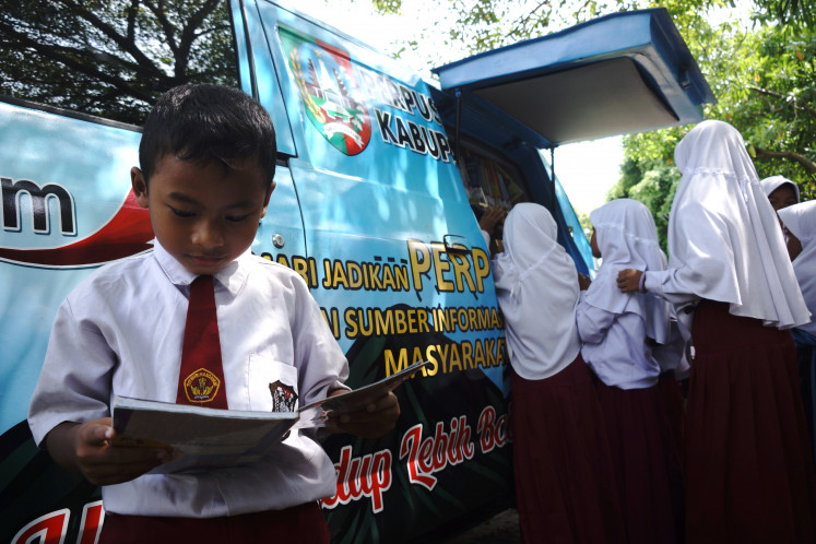 Students take out books from a mobile library on April 23, 2024, World Book and Copyright Day, at SDN Glagahan I state elementary school in Jombang, East Java.