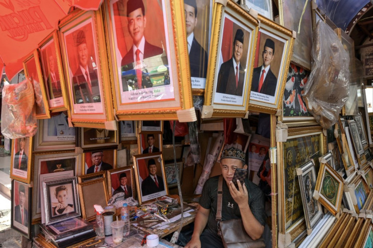 A vendor sells pictures of president-elect Prabowo Subianto (center) and vice president-elect Gibran Rakabuming Raka (right) at his kiosk in Jakarta on April 23, 2024. Pictures depicting the Indonesian president and vice president are mandatory for installation in schools and offices, and many other public spaces.