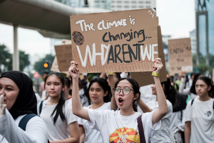 Participants hold placards as they march on a street ahead of Earth Day, the annual environmental-awareness day, in Jakarta on April 21, 2024.
