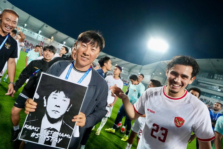 Indonesian U-23 men's national soccer team head coach Shin Tae-yong (left) carries a poster of his portrait after the team secures a win against South Korean team during the 2024 AFC U-23 Asian Cup quarter final match at Abdullah bin Khalifa Stadium in Doha, Qatar on April 25, 2024.