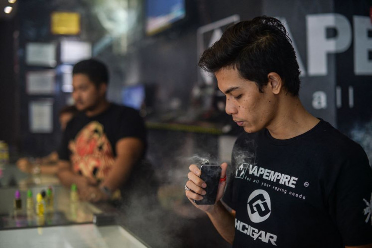 A worker (right) inspects a coil, the metal heating element in an e-cigarette that produces vapor from e-juices, at a vape shop in Kuala Lumpur, Malaysia on Nov. 19, 2015.