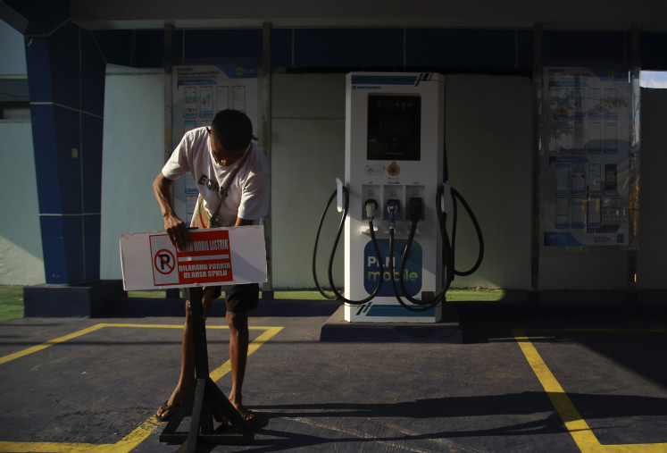 A man adjusts a sign on April 26, 2024, at an electric vehicle charging station in Ternate, North Maluku.