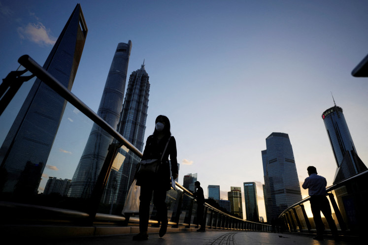 People walk on an overpass past office towers in the Lujiazui financial district of Shanghai, China, on Oct. 17, 2022.