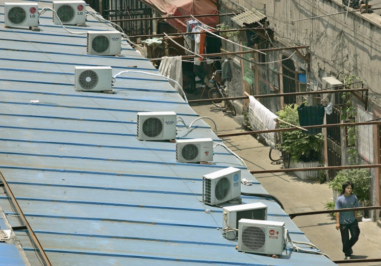 A man walks under a roof where a row of air conditioners are installed, 07 June 2005, in Shanghai.  