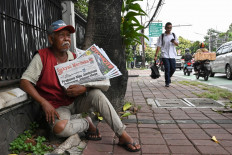 A man sells newspapers on the street in Jakarta on March 27, 2024.