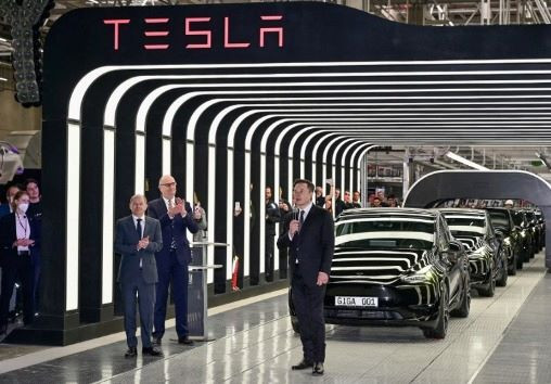 German Chancellor Olaf Scholz (left) and Brandenburg State Premier Dietmar Woidke (center) applaud as Tesla CEO Elon Musk speaks at an event on March 22, 2022 to kick-start production at Tesla's gigafactory in Gruenheide, southeast of Berlin.