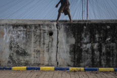 A person walks on a cracked seawall on May 7, 2024, in Kalibaru, Cilincing, North Jakarta. Residents of the
area fear that the wall, which was built to protect the area from waves and tides, could collapse at any time.
