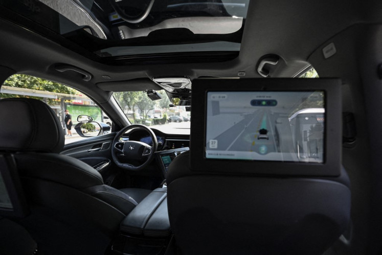 This photo taken on July 17, 2023, shows a driverless robotaxi autonomous vehicle developed by Baidu Apollo driving along a street in Beijing. Struggling foreign automakers in China are looking for help from local tech giants to try and stay competitive in the world's biggest electric car market, where shiny smart screens, assisted driving and sophisticated map technology are in high demand.