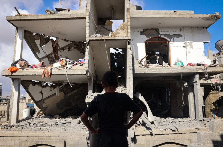 A Palestinian youth stands in front of a destroyed building following an Israeli bombardment of Rafah's Tal al-Sultan district in the southern Gaza Strip on May 7, 2024. The Israeli army said it took “operational control“ of the Palestinian side of the Rafah border crossing between Gaza and Egypt on May 7 and that troops were scanning the area.