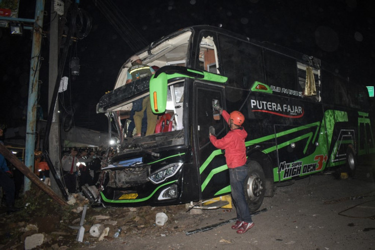 Officers check the damaged bus after a crash that killed 11 people, according to local police, in Subang, West Java, on May 11, 2024. 