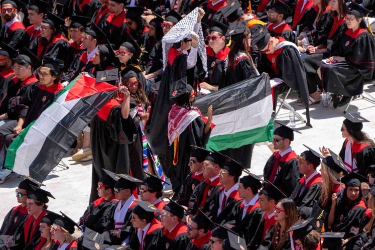 Graduates protesting the Israel-Hamas war hold Palestinian flags as they walk out during commencement at Camp Randall Stadium at the University of Wisconsin-Madison in Madison, Wisconsin, US May 11, 2024. 