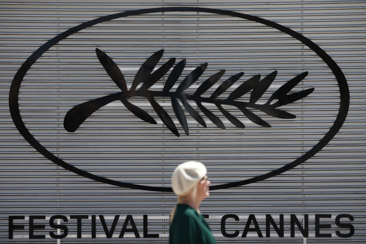 A woman walks on May 13, 2024, past a Palme d'Or symbol on the eve of the opening of the 77th Cannes Film Festival in Cannes, France.