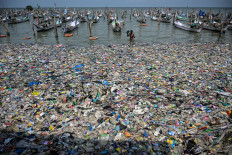 A fisherman returns to shore on May 13, 2024, through a mass of trash on the beach in Bangkalan, Madura Island, East Java. Indonesia is the second-largest producer of plastic waste after China, according to the United Nations Environment Program (UNEP).