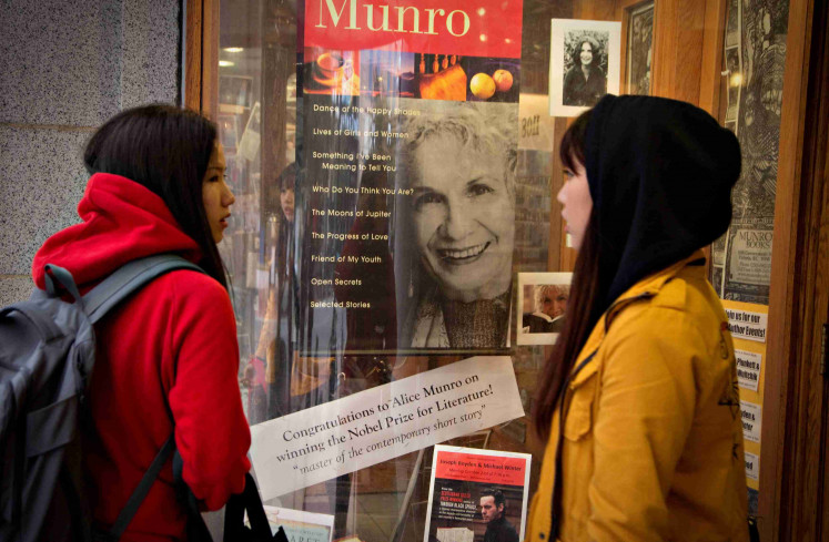 Customers look at a window display congratulating Canadian author Alice Munro at bookstore Munro's Books after she won the Nobel Prize for Literature in Victoria, British Columbia October 10, 2013.