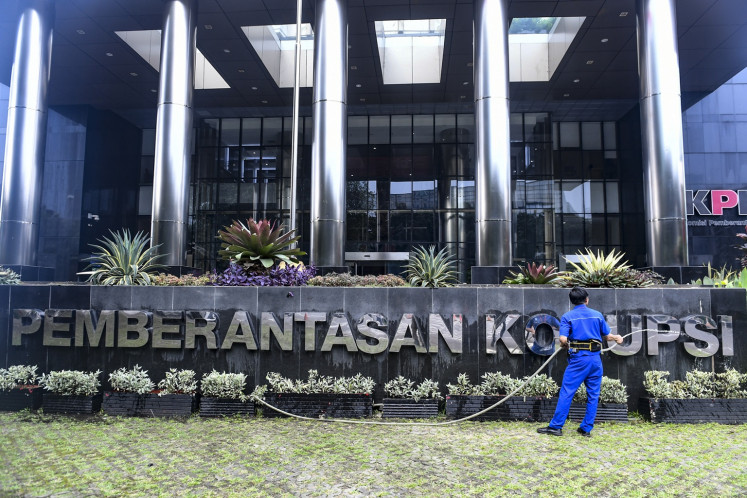 A worker cleans a signage of the Corruption Eradication Commission (KPK) headquarters in Jakarta on April 25, 2024.