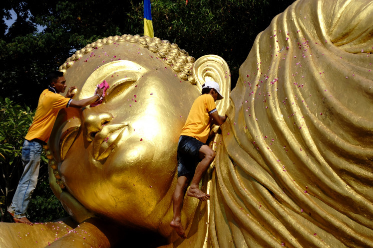 Workers clean a Buddha statue on May 15, 2024, at the Maha Vihara Mojopahit Bejijong complex in Trowulan, Mojokerto, East Java. Measuring 22 meters long, 6 m wide and 4.5 m tall, the statue must be cleaned ahead of Waisak, which celebrates the Buddha’s birth, enlightenment and death.