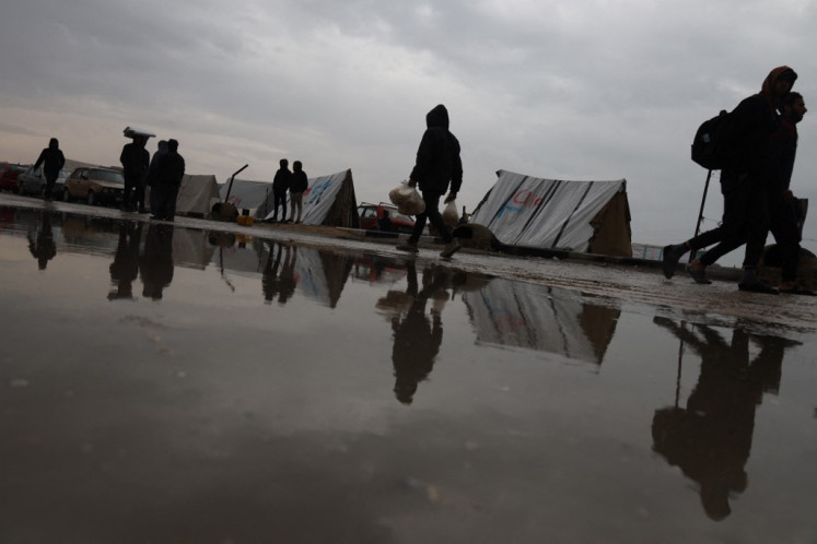 Displaced Palestinians walk past puddles amid rainy weather at a makeshift tent camp in Rafah in the southern Gaza Strip on February 2, 2024, amid ongoing battles between Israel and the Palestinian militant group Hamas. 