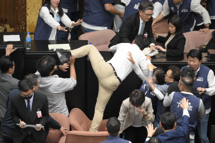 Taiwanese lawmaker Kuo Kuo Wen (center) of the ruling Democratic Progressive Party (DPP) attempts to jump onto a desk on May 17, 2024, during voting for the parliament reform bill at the Legislative Yuan in Taipei, where violence erupted over disputes related to the bill.
