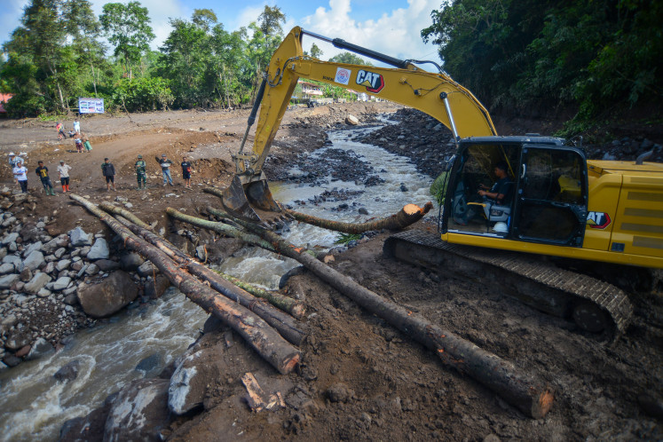 A worker operates an excavator on May 17, 2024, to build a temporary bridge over a river to allow trucks to cross and deliver aid to victims of flooding in Nagari Sungai Bambu, Tanah Datar regency, West Sumatra. Nagari Sungai Bambu remains isolated as vital bridges have been swept away by the floods.
