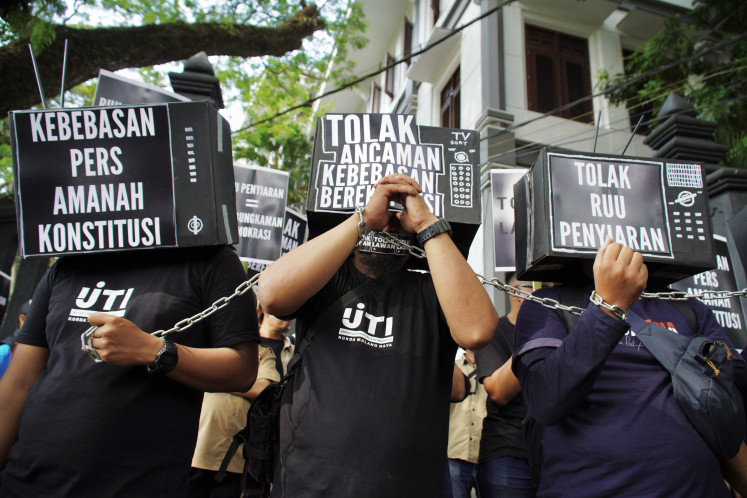 Members of the Indonesian Television Journalists Association (IJTI) with their faces covered with black boxes that read “a free press is a constitutional mandate” and their wrists linked by a chain, demonstrate on May 17, 2024, outside the Blitar Legislative Council, East Java.