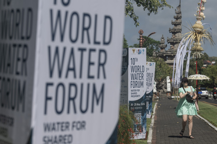 A tourist walks past a World Water Forum billboard on Friday in Nusa Dua, Bali. The resort island is hosting the 10th World Water Forum from May 18-25.