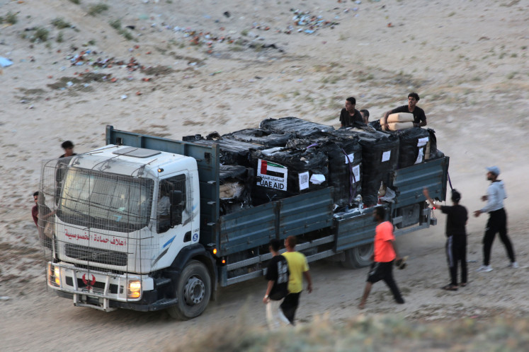 Palestinians rush a truck as it transports international humanitarian aid from the US-built Trident Pier near Nuseirat in the central Gaza Strip on May 18, 2024, amid the ongoing conflict between Israel and the militant group Hamas.