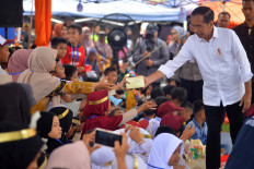 President Joko “Jokowi” Widodo (right) distributes meals on May 21, 2024, to schoolchildren in Nagari Batu Taba, Agam, West Sumatra, where victims of a deadly flood were sheltered.