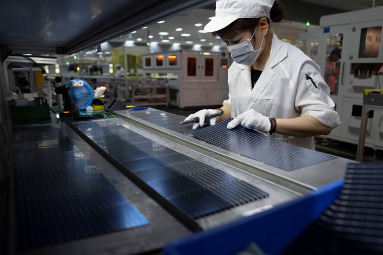 A worker arranges photovoltaic cells on May 16, 2024, at the solar panel factory of GCL System Integration Technology in Hefei, Anhui province, China.