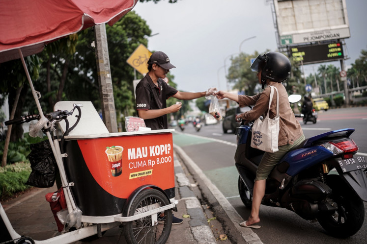 A street vendor sells coffee-to-go on a Jakarta sidewalk on May 28, 2024.
